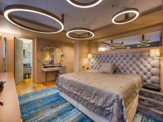 Luxurious bedroom with a plush upholstered headboard, complemented by a stylish oval mirror and a modern vanity.