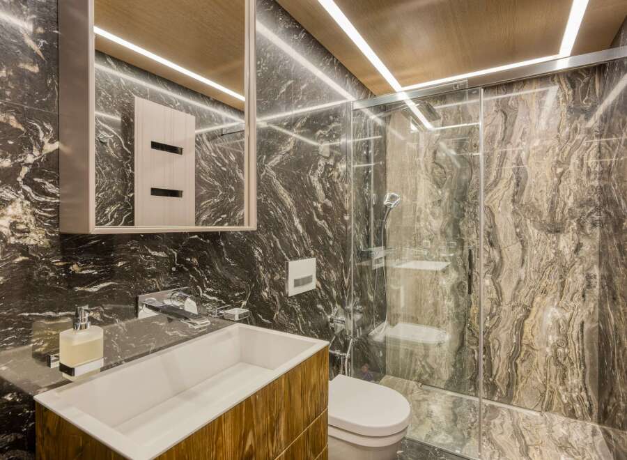 This luxurious bathroom boasts a stunning dark marble design, complemented by modern wooden vanity and sleek chrome fixtures.