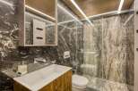 This luxurious bathroom boasts a stunning dark marble design, complemented by modern wooden vanity and sleek chrome fixtures.