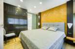This luxurious bedroom boasts a spacious design with built-in dark wood closets and a light gray upholstered bed.