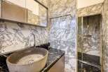 This luxurious bathroom boasts a stunning marble design, featuring a spacious walk-in shower with glass enclosure and a sleek, modern sink.