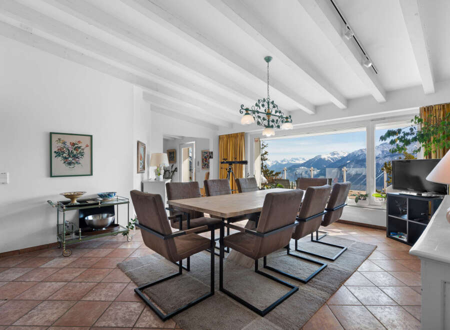 This stunning property boasts a spacious dining area with a large wooden table, modern chairs, and a beautiful chandelier, perfect for entertaining guests.