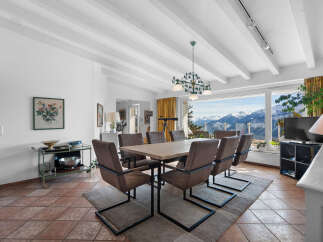 This stunning property boasts a spacious dining area with a large wooden table, modern chairs, and a beautiful chandelier, perfect for entertaining guests.