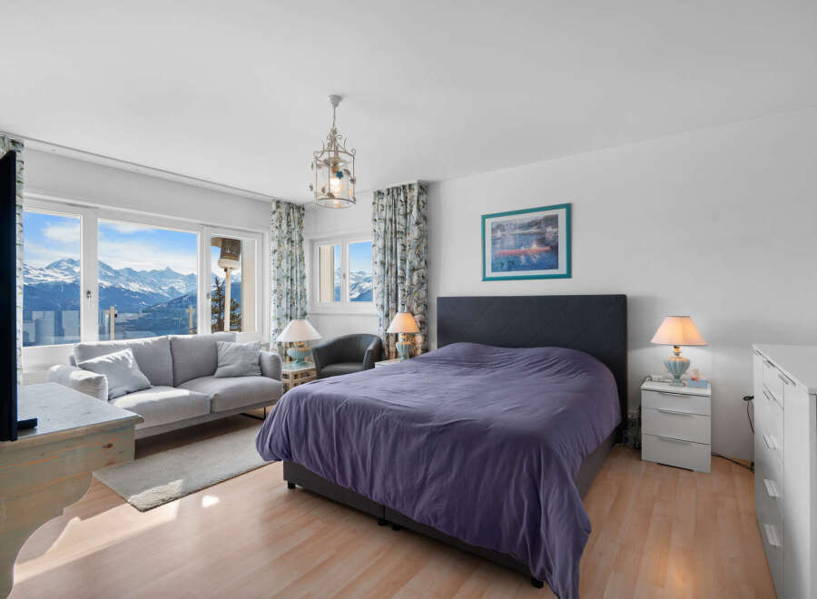 This stunning bedroom boasts breathtaking mountain views from its large windows, creating a serene and relaxing atmosphere.