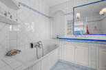 This luxurious bathroom boasts a classic white and blue tile design, complete with a built-in bathtub and spacious vanity.