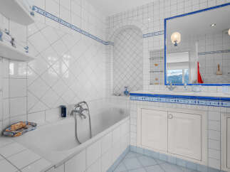 This luxurious bathroom boasts a classic white and blue tile design, complete with a built-in bathtub and spacious vanity.