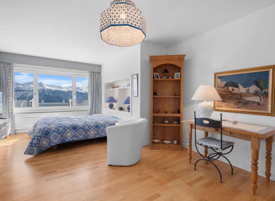 This stunning bedroom boasts breathtaking mountain views from its large windows, creating a serene and tranquil atmosphere.