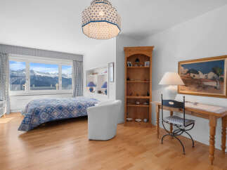 This stunning bedroom boasts breathtaking mountain views from its large windows, creating a serene and tranquil atmosphere.