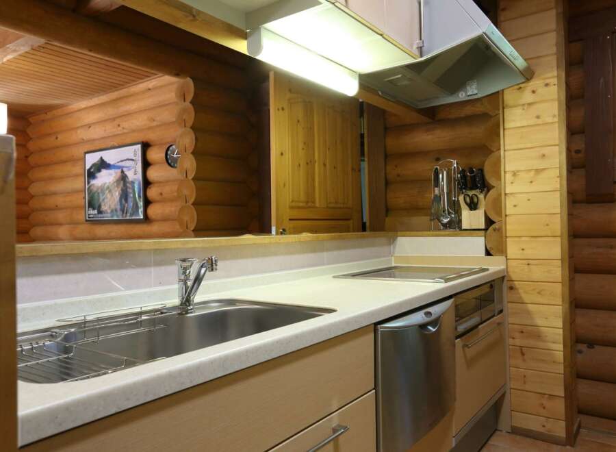 This cozy log cabin kitchen boasts a modern design with stainless steel appliances and light beige countertops.