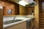 This cozy log cabin kitchen boasts a modern design with stainless steel appliances and light beige countertops.