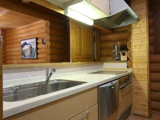 This cozy log cabin kitchen boasts a modern design with stainless steel appliances and light beige countertops.
