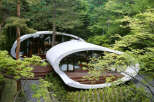 Nestled in a lush forest, this unique home boasts a stunning, modern design with curved concrete walls and expansive windows offering breathtaking views.