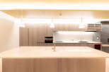 Modern kitchen with sleek light wood cabinetry, marble countertops, and integrated appliances.