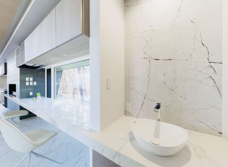 This stunning modern kitchen boasts sleek cabinetry, a built-in grill, and expansive window views.