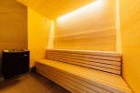Indulge in ultimate relaxation in this exquisite sauna, featuring a spacious wooden bench and a sleek, modern heater.