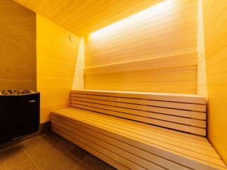 Indulge in ultimate relaxation in this exquisite sauna, featuring a spacious wooden bench and a sleek, modern heater.