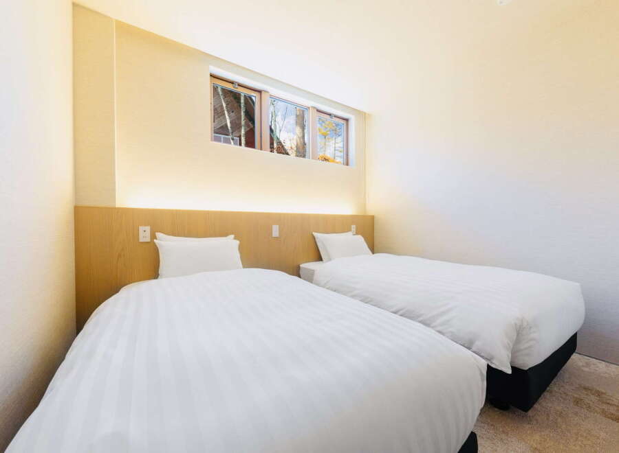 Relax in our cozy twin room, featuring crisp white linens and a light wood headboard.