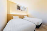 Relax in our cozy twin room, featuring crisp white linens and a light wood headboard.