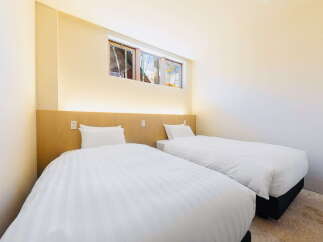 Relax in our cozy twin room, featuring crisp white linens and a light wood headboard.