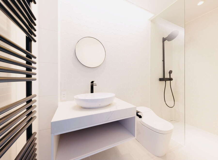 Modern bathroom with white hexagonal tiles, a sleek floating vanity, and a frameless glass shower enclosure.