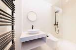 Modern bathroom with white hexagonal tiles, a sleek floating vanity, and a frameless glass shower enclosure.