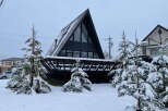 A frame A-frame house nestled in a snowy landscape.