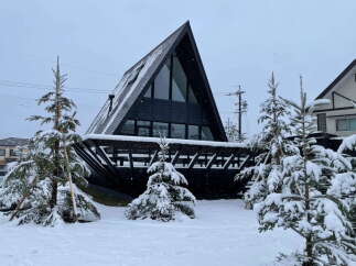A frame A-frame house nestled in a snowy landscape.
