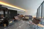 Modern living space with a wood-burning stove, comfortable leather armchairs, and a sleek sofa.