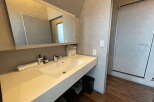 Modern bathroom with sleek white sink and vanity, large mirror, and stylish fixtures.