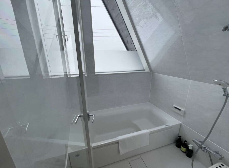 Relax in this serene bathroom featuring a modern bathtub and a large window offering natural light.