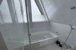 Relax in this serene bathroom featuring a modern bathtub and a large window offering natural light.
