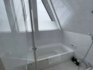 Relax in this serene bathroom featuring a modern bathtub and a large window offering natural light.