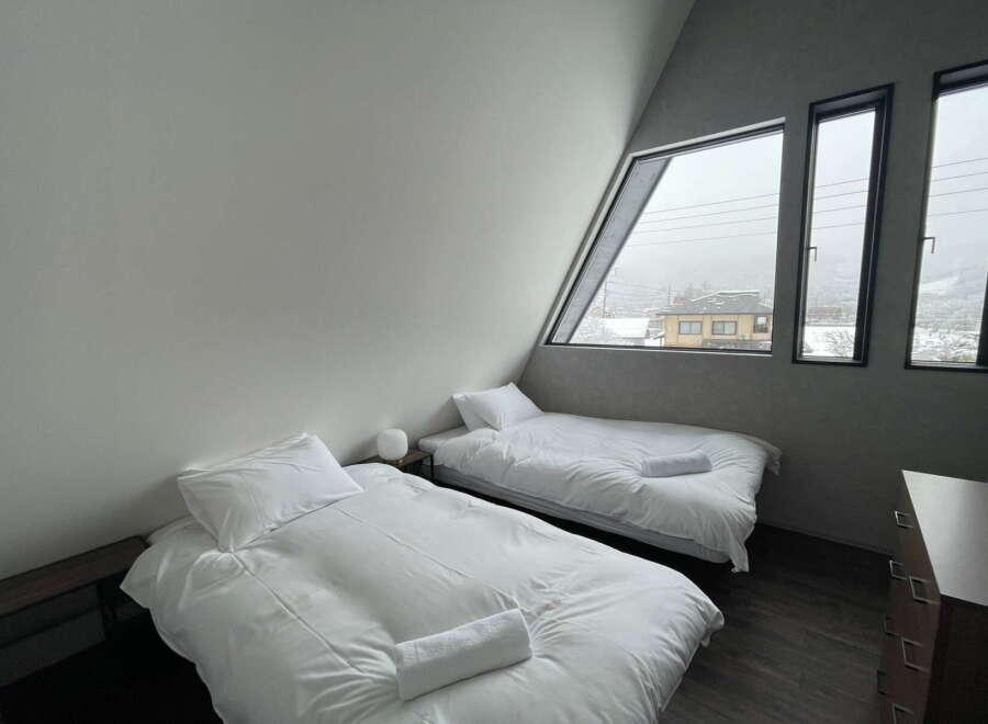 Wake up to stunning views from this cozy bedroom with two single beds and large windows.