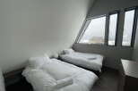 Wake up to stunning views from this cozy bedroom with two single beds and large windows.