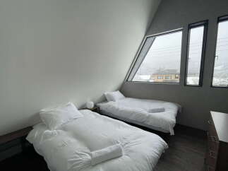 Wake up to stunning views from this cozy bedroom with two single beds and large windows.