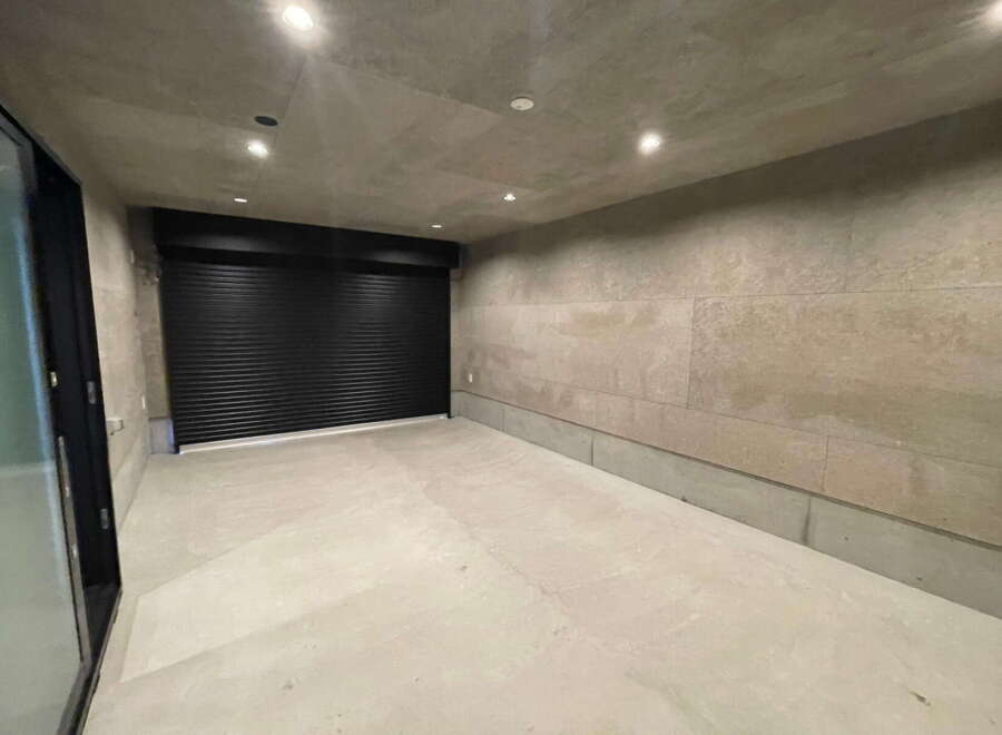 Modern minimalist garage with sleek black roll-up door and polished concrete floor.
