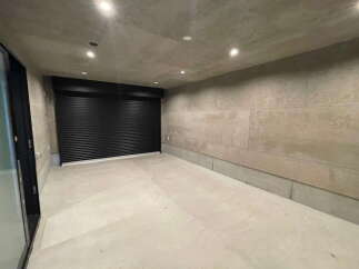 Modern minimalist garage with sleek black roll-up door and polished concrete floor.