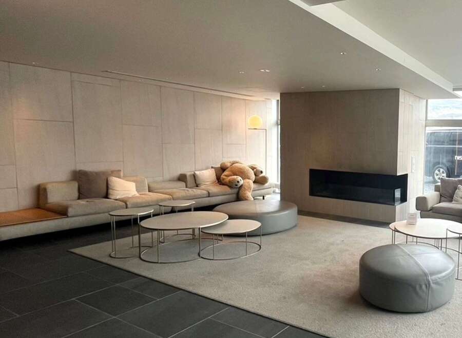 Modern minimalist living space featuring a large sectional sofa, plush rug, and sleek coffee tables.