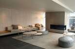 Modern minimalist living space featuring a large sectional sofa, plush rug, and sleek coffee tables.