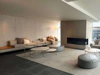 Modern minimalist living space featuring a large sectional sofa, plush rug, and sleek coffee tables.