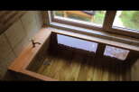 Indulge in tranquility with this exquisite wooden bathtub, perfectly nestled near a window offering serene garden views.