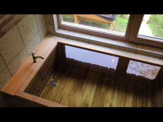 Indulge in tranquility with this exquisite wooden bathtub, perfectly nestled near a window offering serene garden views.