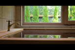 Relax in this luxurious bathroom featuring a wooden bathtub and a vintage-style faucet.