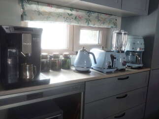 This stunning kitchen boasts a full suite of high-end appliances, including a DeLonghi espresso machine, Smeg coffee maker, and stylish pastel-colored kettle and toaster.
