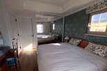 This charming bedroom boasts a king-size bed with crisp white linens and floral pillows, creating a serene atmosphere.
