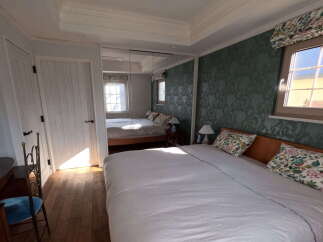 This charming bedroom boasts a king-size bed with crisp white linens and floral pillows, creating a serene atmosphere.