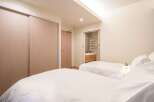 This luxurious bedroom features twin beds with crisp white linens, a built-in closet with sliding doors, and an ensuite bathroom with modern fixtures.
