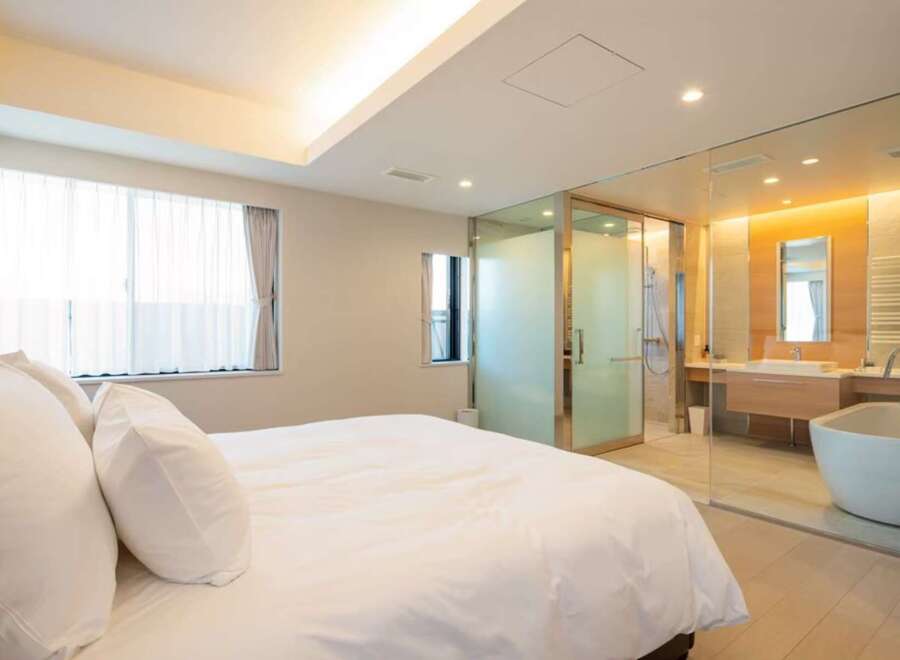 Luxurious bedroom with ensuite bathroom featuring a freestanding bathtub and glass enclosure.