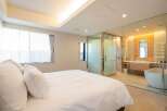 Luxurious bedroom with ensuite bathroom featuring a freestanding bathtub and glass enclosure.