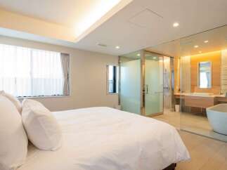 Luxurious bedroom with ensuite bathroom featuring a freestanding bathtub and glass enclosure.
